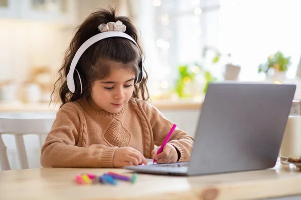Ensino à Distância. Menina bonito em fones de ouvido estudo com laptop em casa — Fotografia de Stock