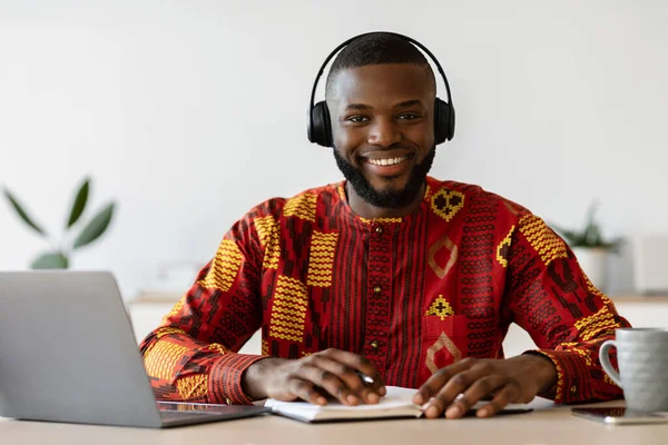 E-learning. Gelukkig zwarte man dragen headset studie online met laptop thuis — Stockfoto