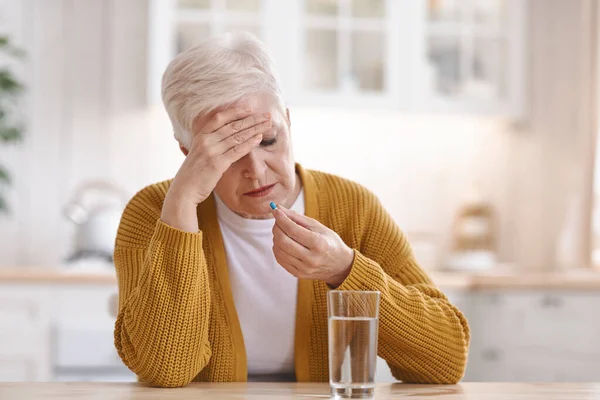 Vecchia donna che soffre di mal di testa, prendendo la pillola — Foto Stock