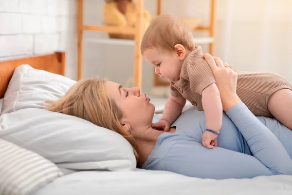 Vacker liten bebis låg på lycklig mor mage — Stockfoto
