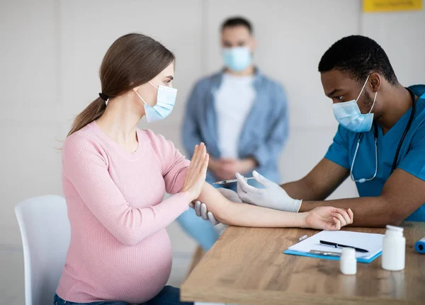 Mujer embarazada impidiendo que el trabajador médico haga la vacuna covid-19, oponiéndose a la inmunización contra el coronavirus en la clínica — Foto de Stock