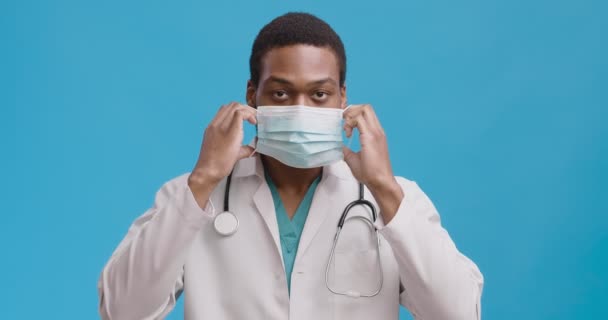 Protección personal y nueva normalidad. Joven médico afroamericano que se pone mascarilla protectora — Vídeo de stock