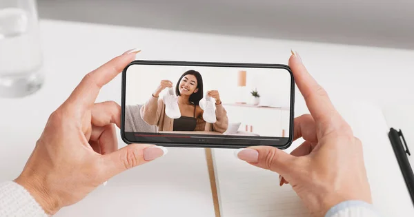 Mujer milenaria viendo video revisión de zapatos deportivos por el famoso blogger de moda en el teléfono móvil —  Fotos de Stock