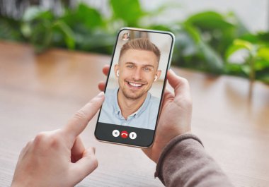 Tanımlanamayan genç bir kadın erkek arkadaşıyla görüntülü görüşme yapıyor, akıllı telefonda internet kuryesi kullanıyor.