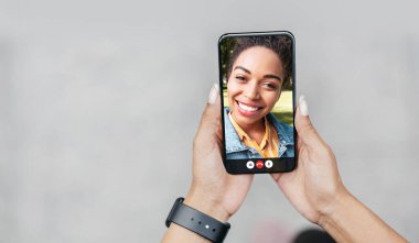 Çevrimiçi iletişim için akıllı telefon. Genç bayan cep telefonundan siyah arkadaşıyla çevrimiçi sohbet ediyor.