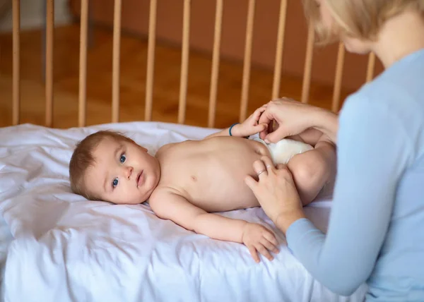 Младенец смотрит в камеру, пока мама меняет пеленки — стоковое фото
