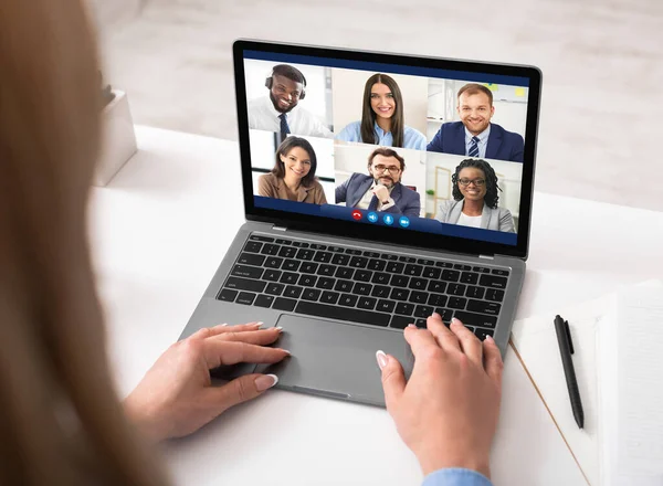 Женщина на ноутбуке проводит видеоконференцию с сотрудниками в помещении — стоковое фото