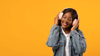 Gülümseyen Afrikalı Amerikalı bayan en yeni stereo kulaklığın keyfini çıkarıyor.