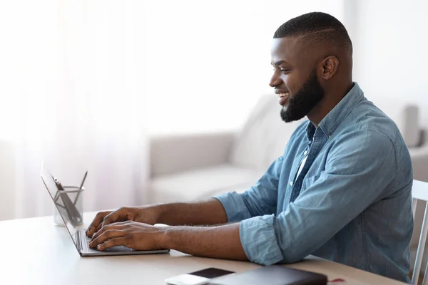Sonriente Millennial afroamericano trabajando con el ordenador portátil en el Ministerio del Interior — Foto de Stock
