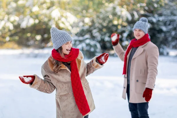 Joyeux jeune couple ayant la bataille de boule de neige à l'extérieur — Photo