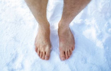 Top view of male feet standing on snow outdoors, cropped. Unrecognizable guy making cold exposure training clipart