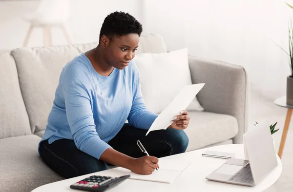 Mujer negra escribiendo informe de trabajo en el ordenador portátil en casa — Foto de Stock