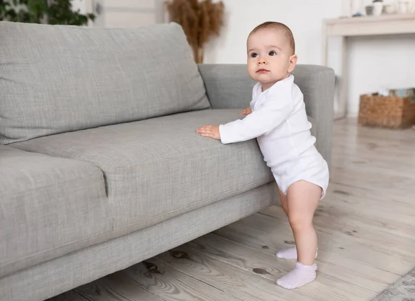 Little Baby Toddler står nära soffan tittar bort hemma — Stockfoto