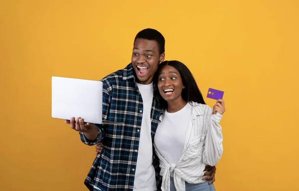 Fröhlich lachender Millennial-Afrikaner mit offenem Mund schaut auf Laptop, Dame hält Kreditkarte — Stockfoto