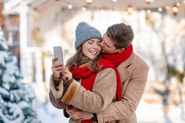 Šťastný pár brát selfie smartphone přes zimní pozadí — Stock fotografie