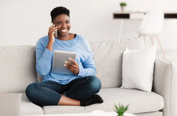 Señora feliz usando la tableta llamando a su amigo, sentado en el sofá — Foto de Stock