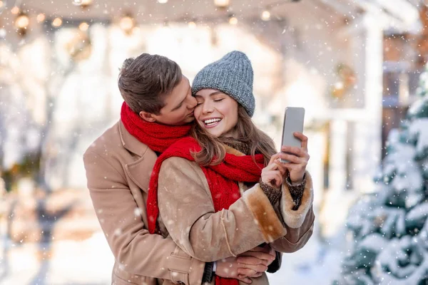 Homem e mulher abraçando e tirando selfie no dia de inverno — Fotografia de Stock