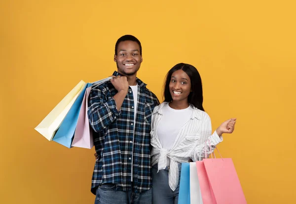 Usmívající se tisíciletý africký americký manžel a manželka držet mnoho barevných balíčků s nákupy po nakupování — Stock fotografie