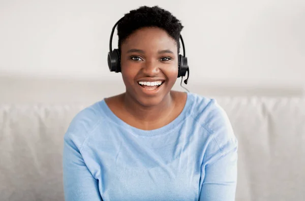 Zwarte vrouw zitten, op zoek naar camera dragen headset — Stockfoto
