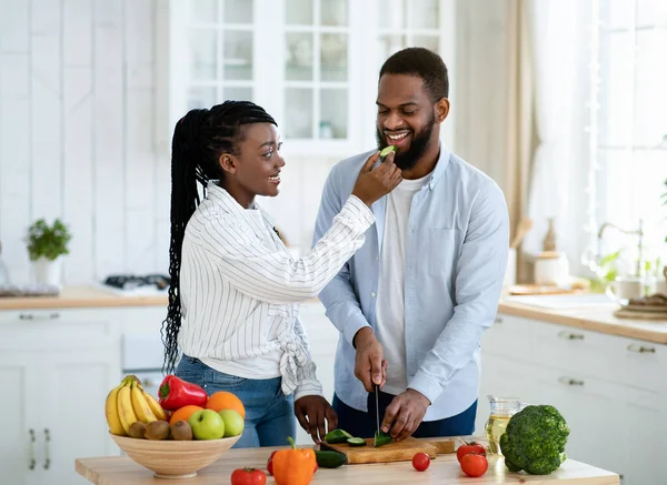 Amar a la mujer negra alimentando a su marido mientras cocinan juntos en la cocina — Foto de Stock