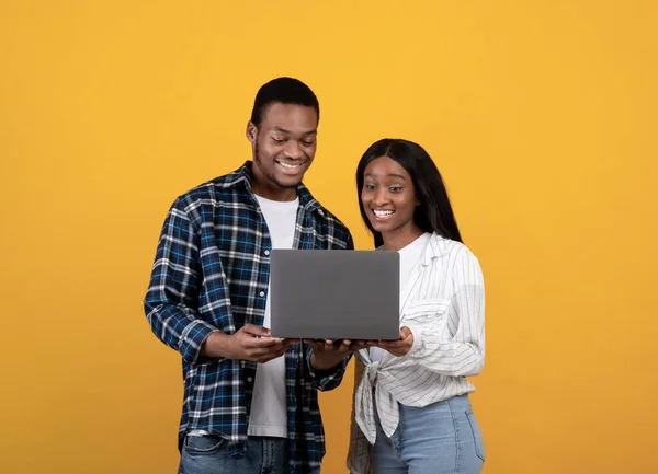 แฮปปี้มิลเลนเนียลแอฟริกันอเมริกันคู่มองไปที่แล็ปท็อปและเลือกซื้อหรือดูบทเรียนหรือวิดีโอ — ภาพถ่ายสต็อก