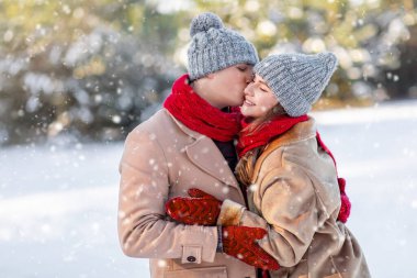 Sevgi dolu bir adam, kış ormanında mutlu sevgilisini öper.