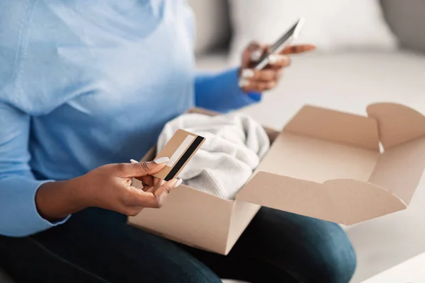 Μαύρη γυναίκα κάθεται με κουτί, πιστωτική κάρτα και smartphone — Φωτογραφία Αρχείου