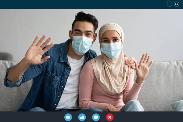 Muslim couple in face masks waving at camera, laptop screen