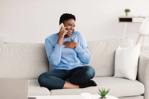 Mulher negra chamando seu amigo, sentado no sofá — Fotografia de Stock
