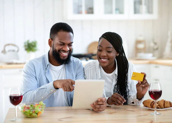 Online Lebensmittel bestellen. Schwarzes Paar mit digitalem Tablet und Karte in der Küche — Stockfoto