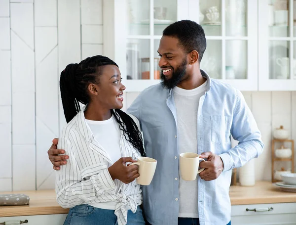 Sorrindo jovem casal afro-americano bebendo café da manhã na cozinha juntos — Fotografia de Stock