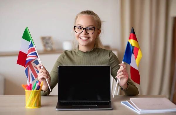 Ευτυχισμένο κορίτσι του σχολείου με σημαίες που δείχνουν άδεια οθόνη laptop — Φωτογραφία Αρχείου