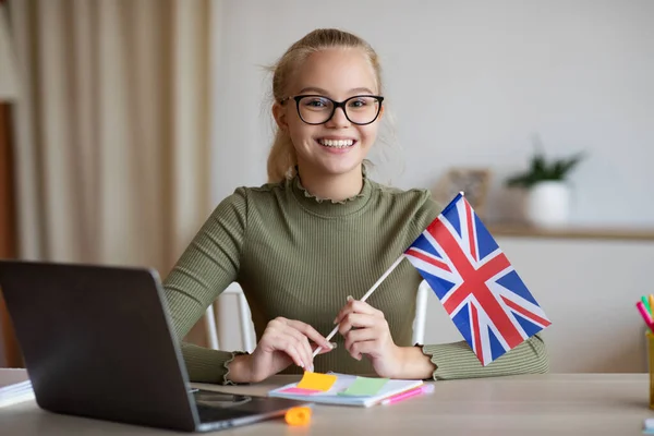 Chica sonriente con bandera de Gran Bretaña utilizando el ordenador portátil — Foto de Stock