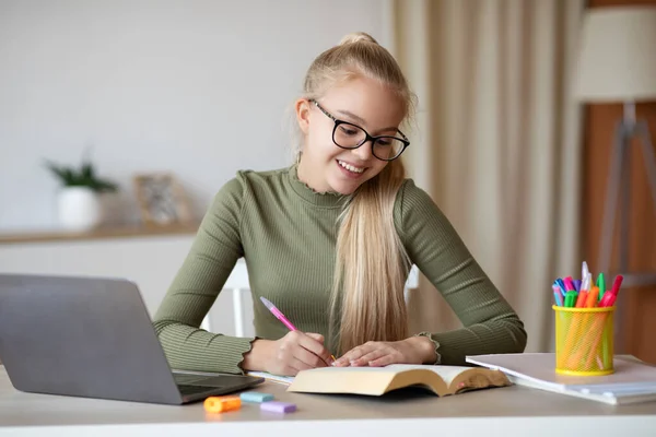 Happy blonde school girl doing homework at home — Stock Photo, Image