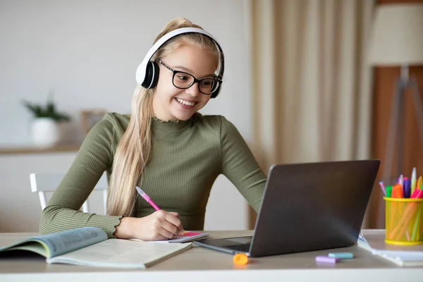 Menina da escola positiva estudando de casa na frente do laptop — Fotografia de Stock