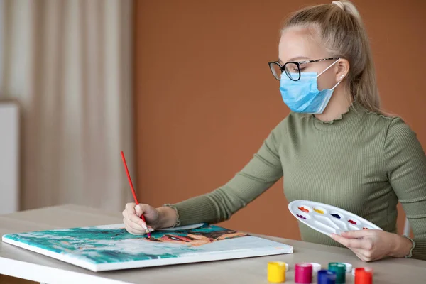 Girl in face mask with palette and brush drawing