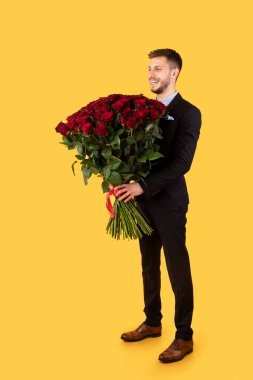 Sarı Arkaplan Üzerinde Kırmızı Güller Çiçeği Tutan Erkek Arkadaş