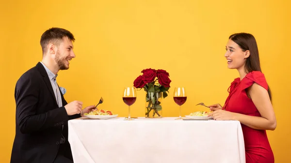 Casal feliz conversando jantando no fundo amarelo, Studio Shot — Fotografia de Stock