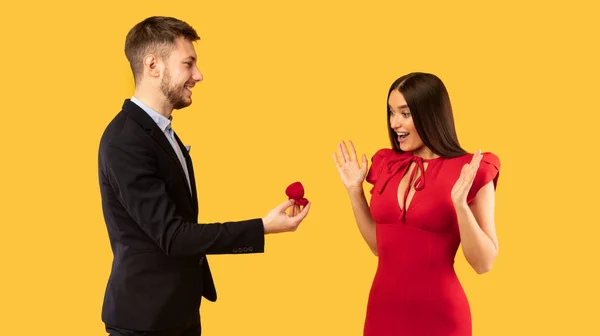 Mężczyzna oświadczając się kobiecie dając pierścionek na żółtym tle, Panorama — Zdjęcie stockowe