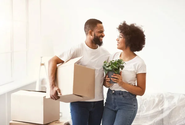 Cônjuges negros alegres transportando caixas se movendo para novo apartamento — Fotografia de Stock