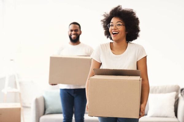 Взволнованная африканская пара, перевозящая коробки, входящие в собственный дом