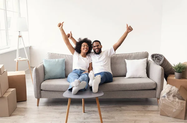 Joyful Black Couple Gesturing Thumbs-Up Celebrating Moving to New House — стоковое фото