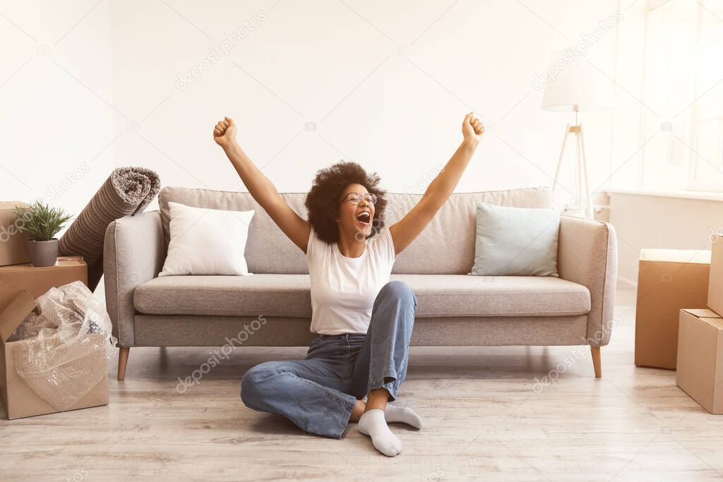 Joyful Black Woman Sitting Among Moving Boxes After Relocation Indoors