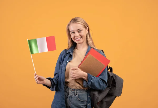 Not defterleri, sırt çantaları ve küçük bayrağıyla gülümseyen kadın üniversiteye gidiyor. — Stok fotoğraf