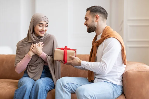 Musulman mari surprenant femme avec un cadeau assis à la maison — Photo