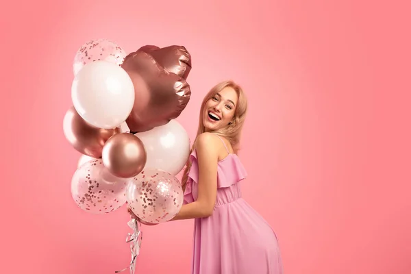 Jeune dame insouciante avec des ballons de vacances faire la fête, célébrer anniversaire ou anniversaire sur fond de studio rose — Photo