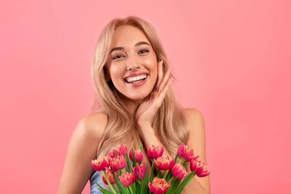 Portrait de jeune femme joyeuse avec bouquet de printemps romantique de tulipes sur fond rose. Fête de la femme — Photo