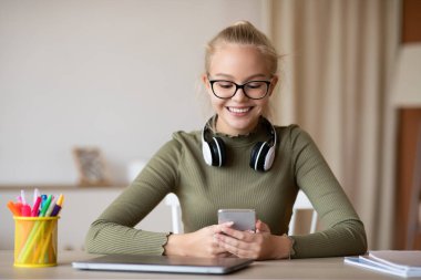 Evde cep telefonu kullanan neşeli bir genç kız.