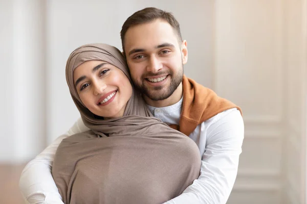 Alegre jovem muçulmano casal abraçando posando em pé dentro de casa — Fotografia de Stock