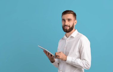 Formalite icabı yeni yetme bir adam çevrimiçi iş için tablet bilgisayar kullanıyor ya da mavi arkaplan üzerine çalışıyor.